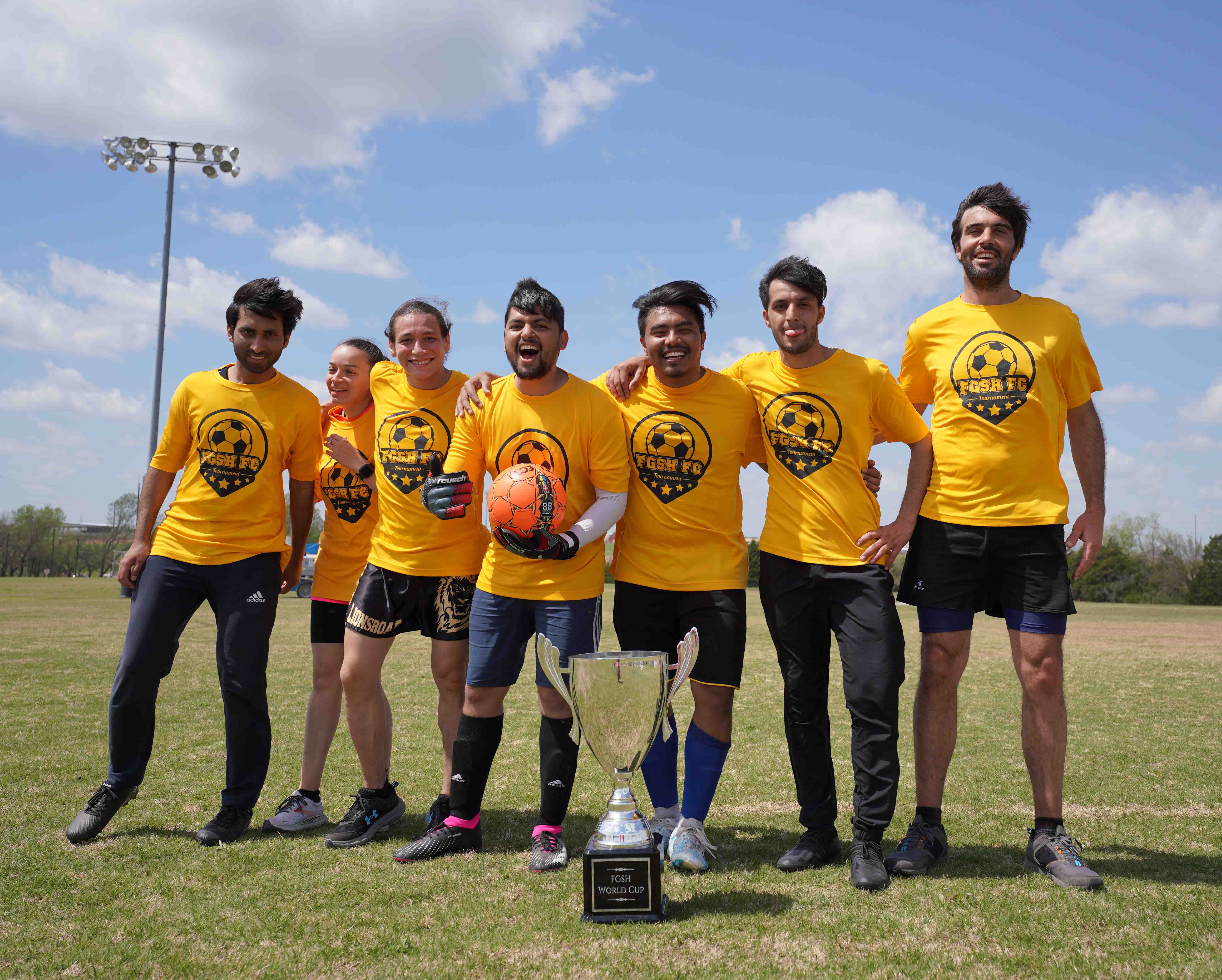 FGSH Soccer Tournament team smiling at fgsh soccer tournament. one student holding a soccer ball. trophy in front of them.